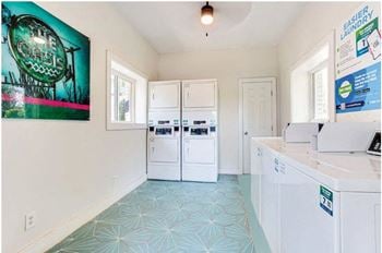 A laundry room with two white washers and a washer and dryer